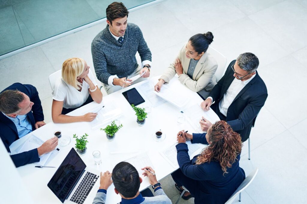 Zdjęcie ilustracyjne - pracownicy biurowi rozmawiający przy stole