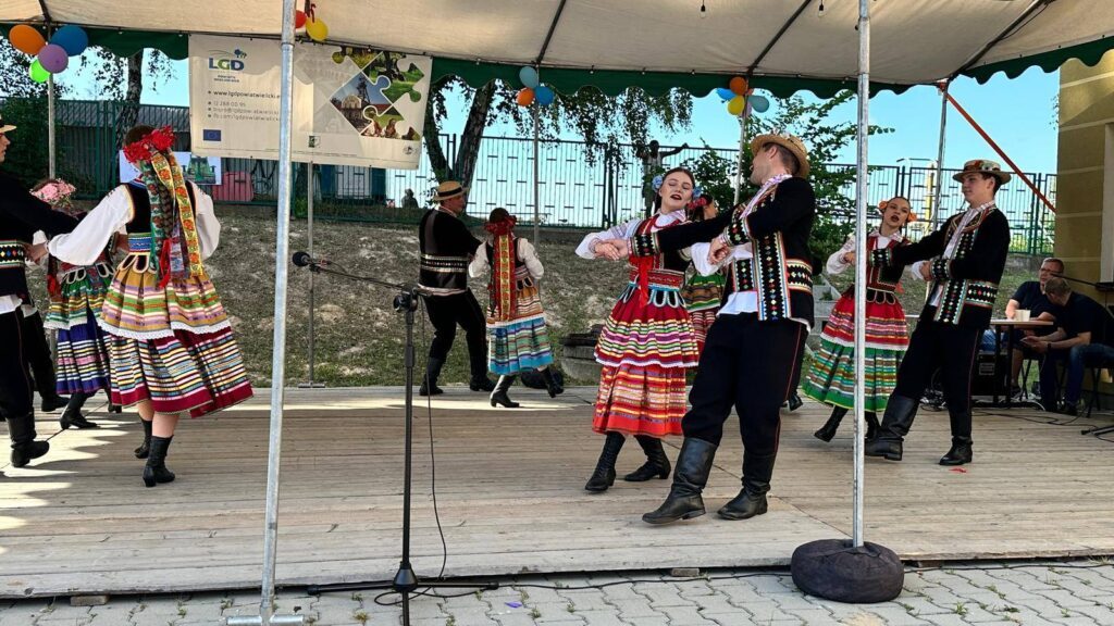 Młodzież w strojach ludowych tańcząca na scenie