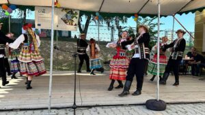 Młodzież w strojach ludowych tańcząca na scenie