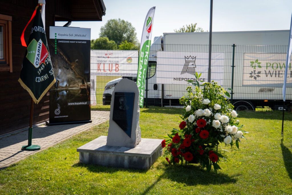 Widok na pomnik, sztandar drużyny oraz złożone kwiaty