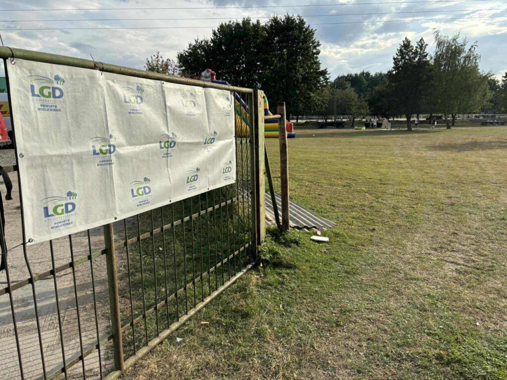 Działka z dmuchaną zjeżdżalnią w tle, czekające na przybycie zabawowiczów.